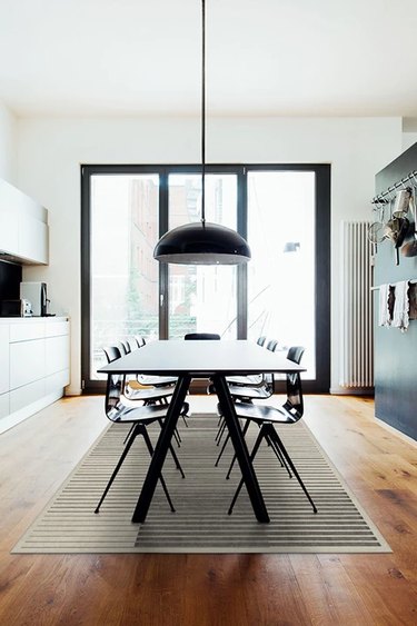 modern dining room with pendant light and striped rug