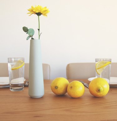 Yahalomis Ceramic Vase with flower and lemons sitting on a table.