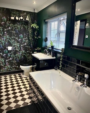 Black bathroom with floral wallpaper and checkered flooring.