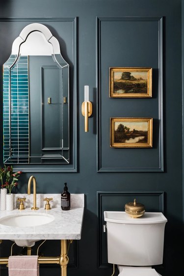 Navy bathroom with wall trim and golden accents.