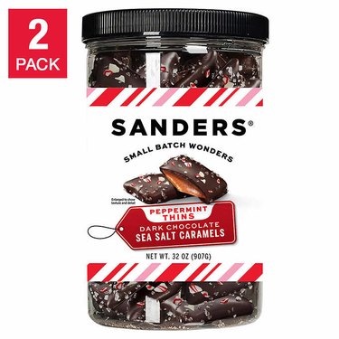 A clear plastic jar filled with dark chocolate sea salt caramels. The label reads "Sanders small batch wonders. Peppermint thins, dark chocolate sea salt caramels."