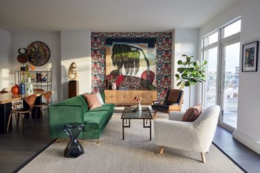 Living room with a patterned accent wall and green velvet couch