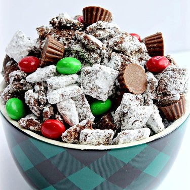 A bowl of Muddy Buddies with tiny Reese's cups and Christmas-colored M&M's.