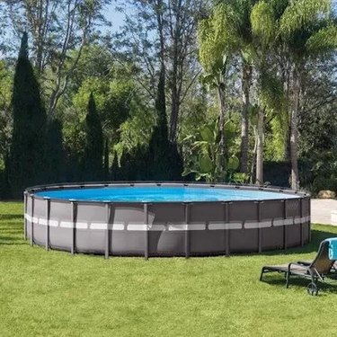 An Intex above-ground pool in a backyard full of trees