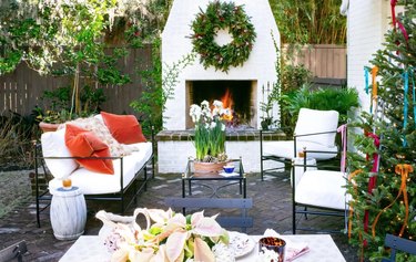 Patio with outdoor fireplace, couch, chairs, holiday decor.