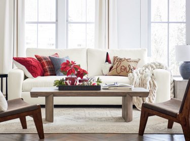 Living room with white couch, holiday pillows, accent chairs, coffee table, area rug.