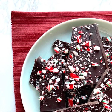 Peppermint chocolate bark on a white plate on a red cloth.