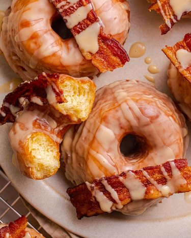 A close-up image of maple bacon donuts with strips of bacon on top