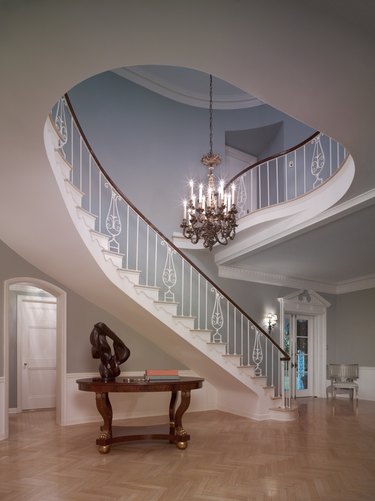 spiraling staircase with chandelier and white ceiling