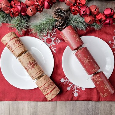 table with red table runner and two christmas crackers on white plates