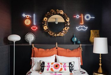 dark blue bedroom with two abstract face neons on either side of mirror