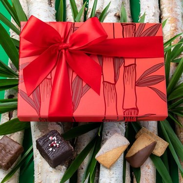 red bamboo gift box with chocolates and baked goods nearby