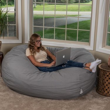 woman sitting with computer on a gray pouf