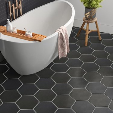 A concrete-like porcelain tile in a hexagon pattern with a freestanding bathtub