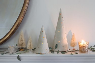 DIY clay holiday tree luminaries on mantel with bottle brush trees and greenery