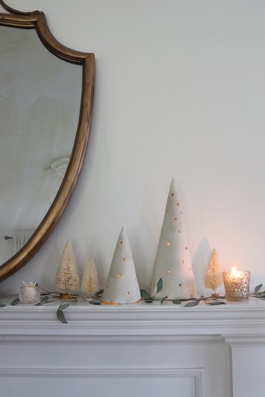 DIY clay holiday tree luminaries on mantel with bottle brush trees and greenery