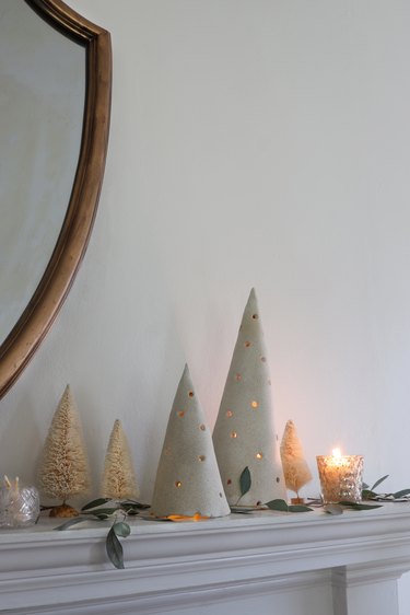 DIY clay holiday tree luminaries on mantel with bottle brush trees and greenery