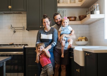 Dark gray cabinets, open shelves, apron sink, white subway tiles.