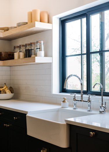 Apron sink, faucet, open shelves, subway tile, storage jars.