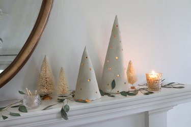 DIY clay holiday tree luminaries on mantel with bottle brush trees and greenery