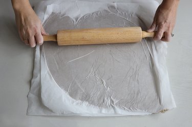 Rolling clay placed between two sheets of wax paper flat