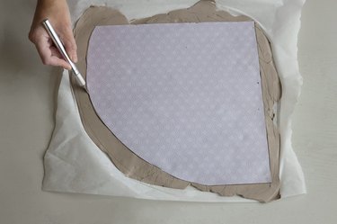 Cutting out arc shape in clay with paper template