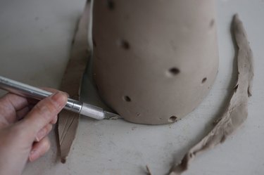 Cutting bottom edge of clay cone to ensure it sits flat