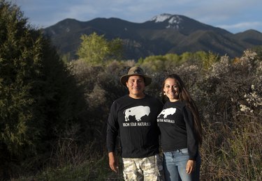 two people in black sweatshirts in front of a natural backdrop