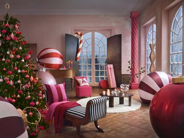 A living room decorated with a Christmas tree covered in pink and red ornaments and other pink and peppermint holiday decor.