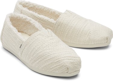 A pair of white West Elm x TOMS slippers