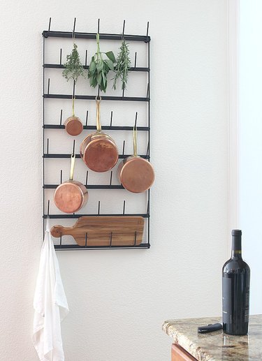 White kitchen with black mug rack and hanging copper pots