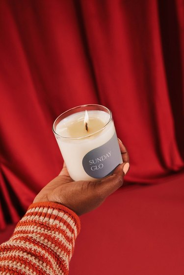 person holding candle in front of red backdrop