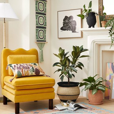fireplace area with bright yellow chair and plants and wall hanging near framed art