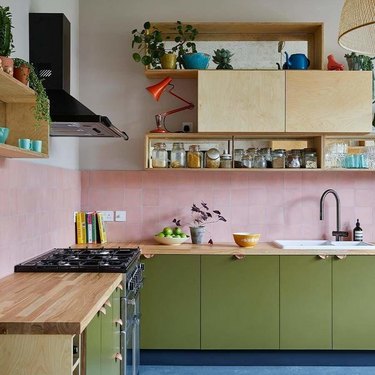 two-tone kitchen color idea with olive green and natural wood cabinetry and pink tiled backsplash