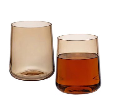 Two amber glasses with one filled with a brown liquid.