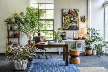 eclectic white office with large abstract artwork, palm plant and ceramic pots with greenery