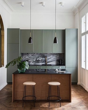 gray-green cabinets with dark marble counters in small kitchen