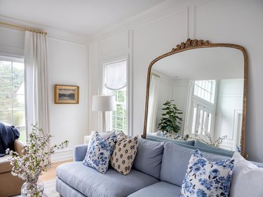 sophisticated mirror with gilded mirror leaning behind a sofa
