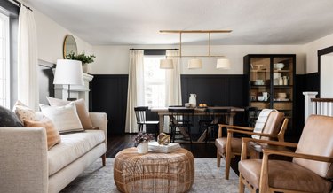 Living room with black wainscoting, leather chairs, beige couch, wicker coffee table