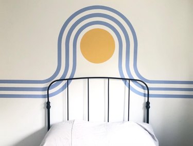 Bed, metal frame, mural on wall.