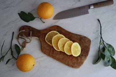 Orange slices arranged on top of cutting board with knife