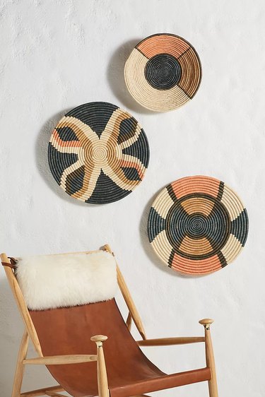 woven baskets hanging on the wall above chair
