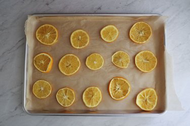 Orange slices on top of parchment-lined baking tray