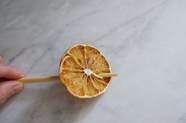 Poking hole through dried orange with wood skewer