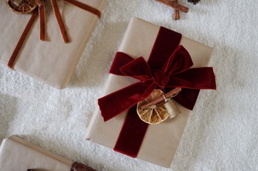 Dried orange gift topper tied to gift wrapped with brown Kraft paper and burgundy velvet ribbon