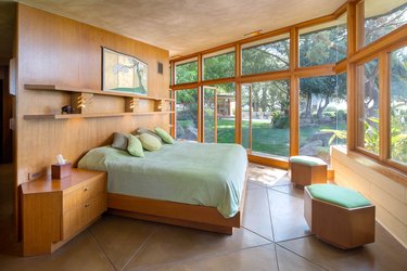Mid century modern bedroom with large windows and light green bed