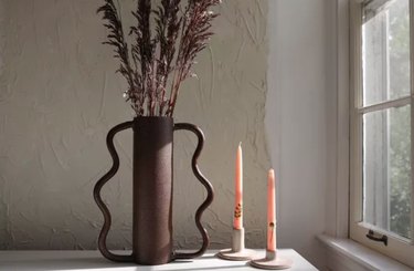 Vase with wavy handles, candle, dried flowers.