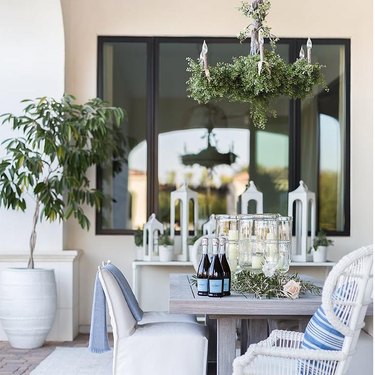 outdoor dining table with chandelier hanging above, draped in vines