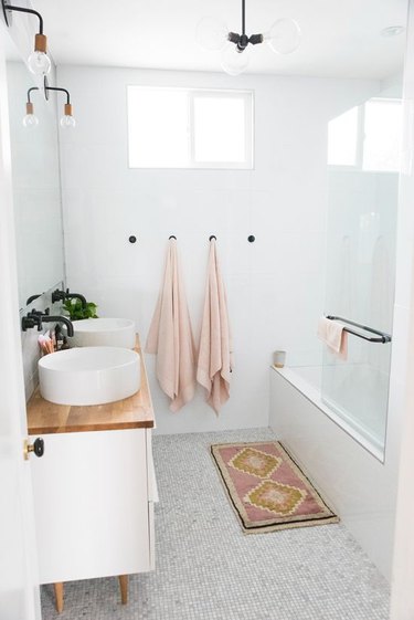 White bathroom with black wall hooks for towels.