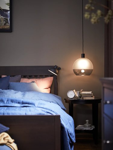 bedroom with blue sheets and hanging lamp